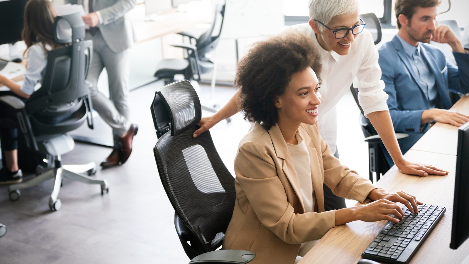 Two business colleagues collaborate at a workstation in a modern office, reviewing AI tool usage across the organization to identify shadow AI exposure.